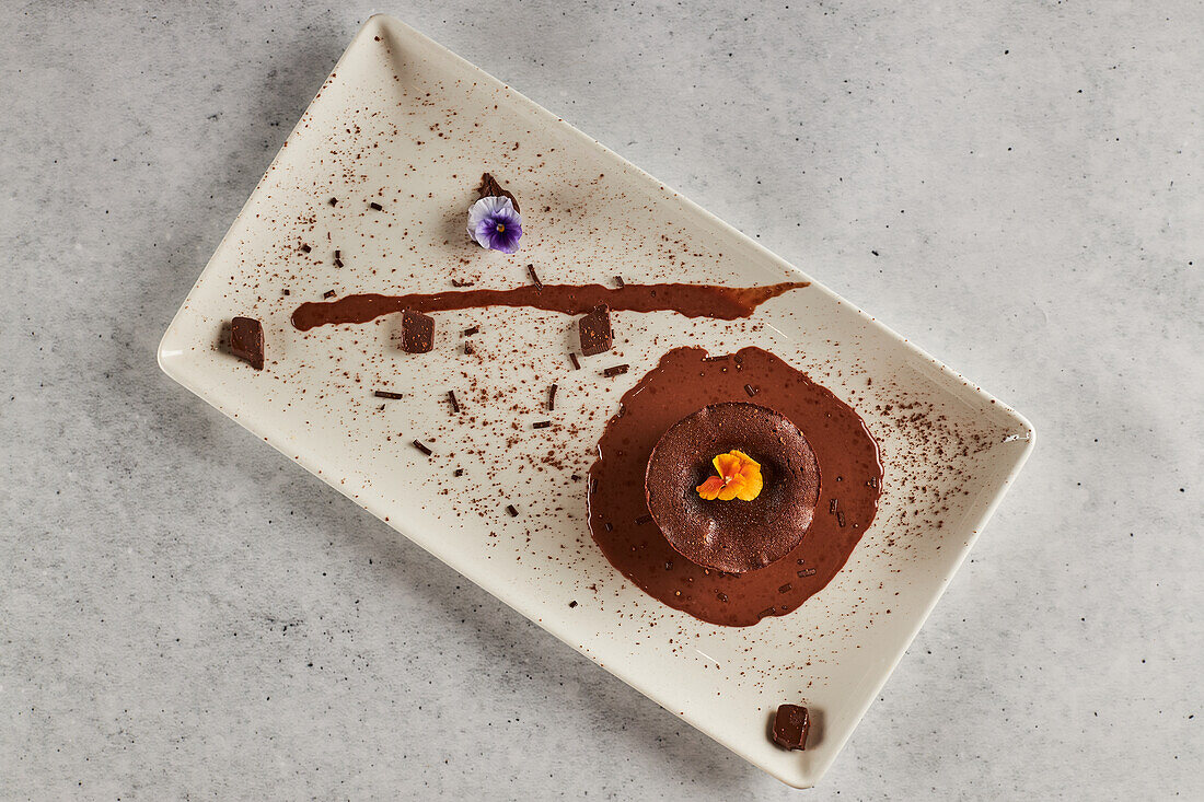 von oben leckerer Schokoladencoulant garniert mit Orangenblüten und serviert auf einem Teller im Restaurant