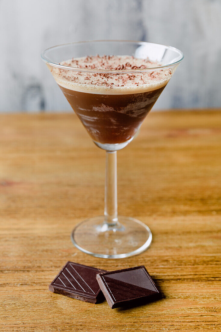 Glass of sweet alcoholic cocktail made of espresso liqueur milk and chocolate placed on wooden table