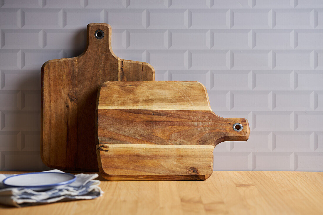 Schneidebretter aus Holz an der Wand auf einem Tisch mit Schüssel in einer hellen Küche