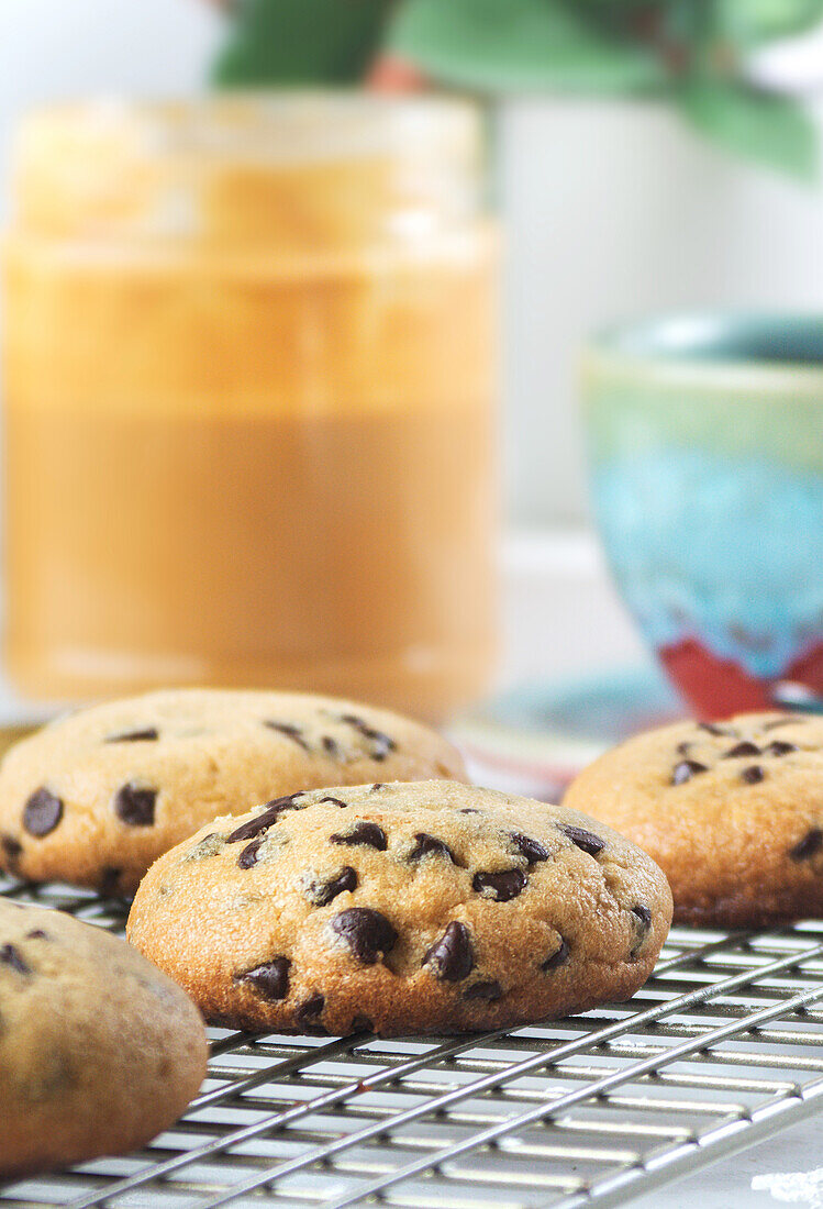 Still life of freshly made chocolate chip cookies with peanut butter and sprinkles next to a coffee