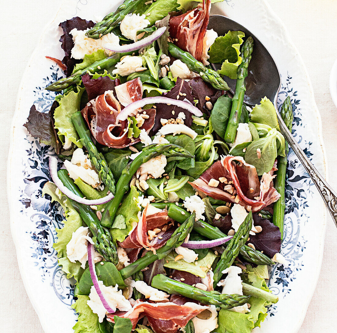From above delicious prosciutto, mozzarella and asparagus salad on white table background