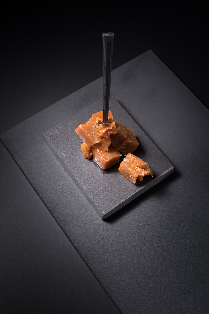 Gourmet-Quittengelee-Paste in Keramikteller auf schwarzem Hintergrund mit Gabel