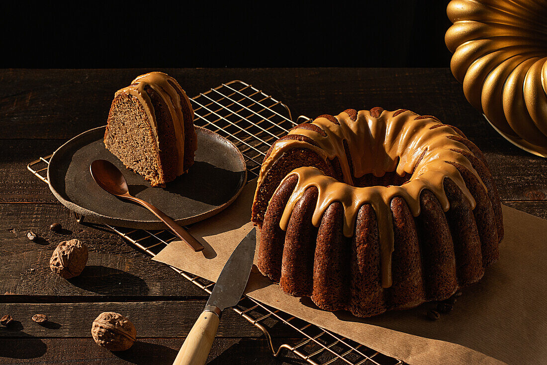 From above coffee walnut bundt cake placed on baking net on dark rustic wooden table in kitchen