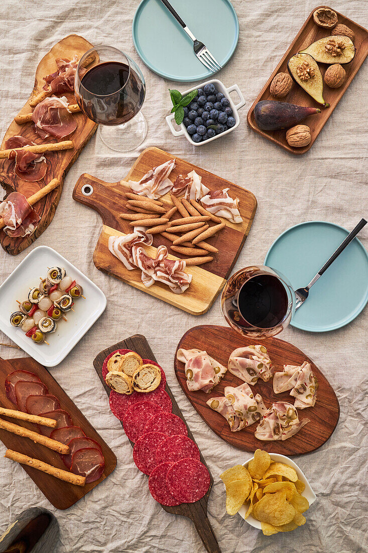 From above of assorted tasty appetizers served on table with tablecloth on terrace