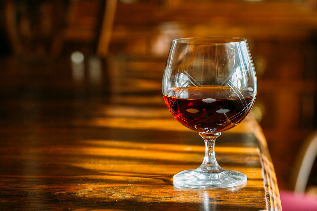 Altmodisches Cognacglas auf Holztisch mit natürlichem Licht