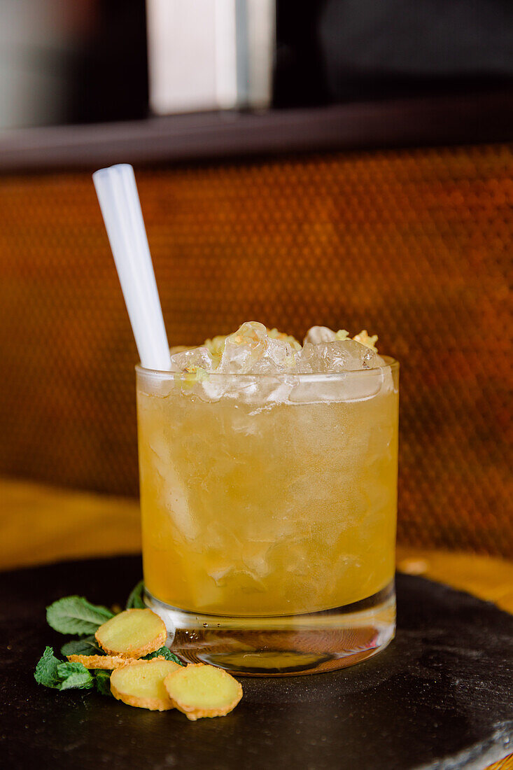 Glas mit saurem Yuzu-Gewürzcocktail aus Alkohol und Saft, serviert mit Ingwerstückchen