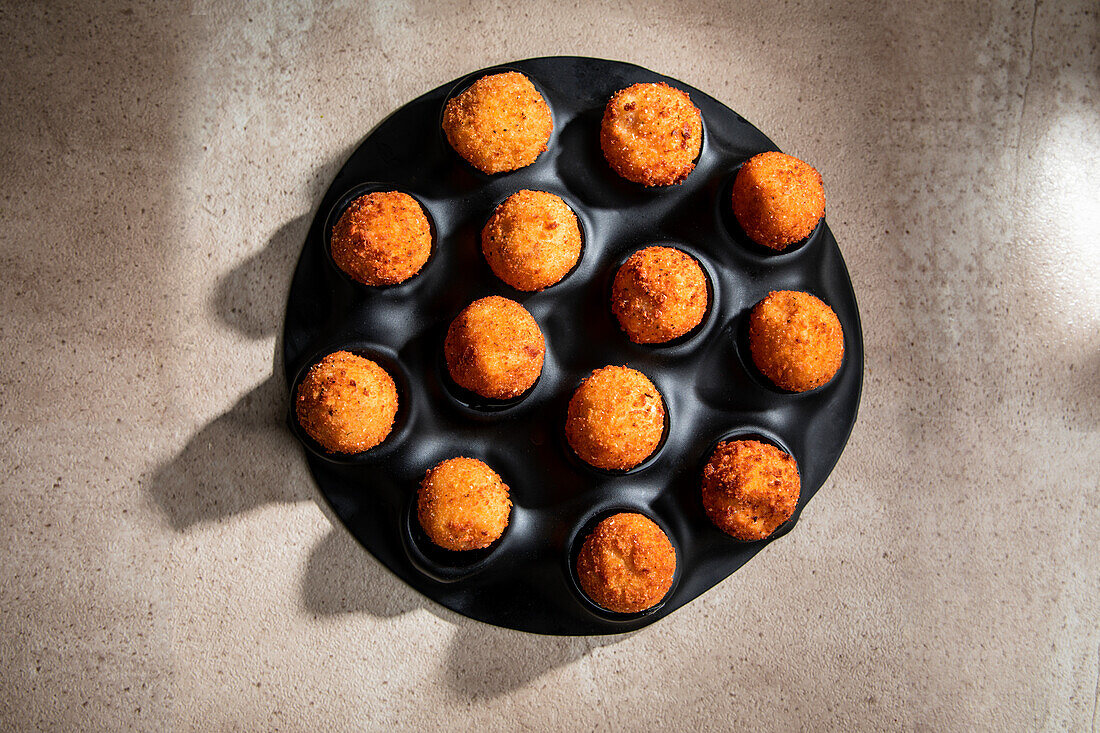 High angle of tasty roasted cheese balls in baking dish on concrete table in the kitchen