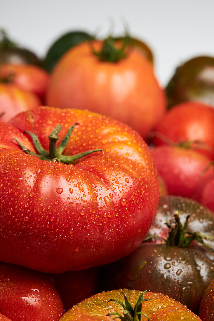 From above of appetizing fresh ripe tomatoes with drops of water with green leaves