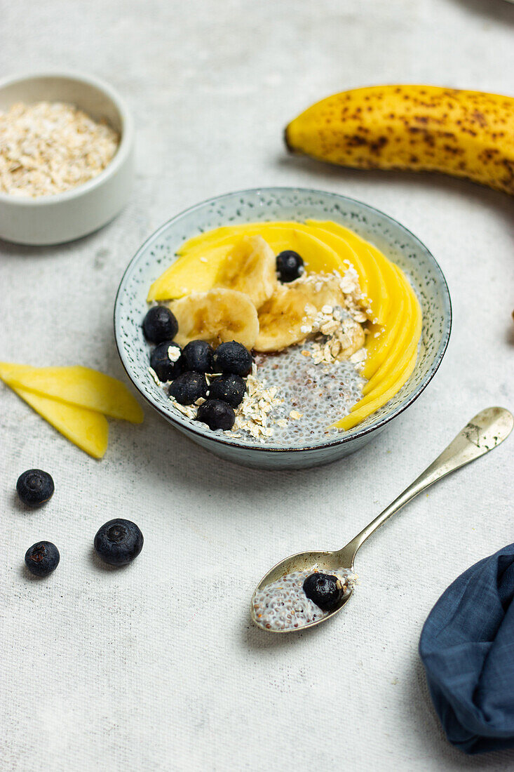 High angle of appetizing healthy muesli with chia seeds slices of banana mango and blueberries for breakfast