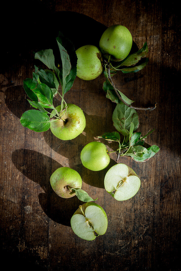 From above ripe green apples with foliage on wooden table background