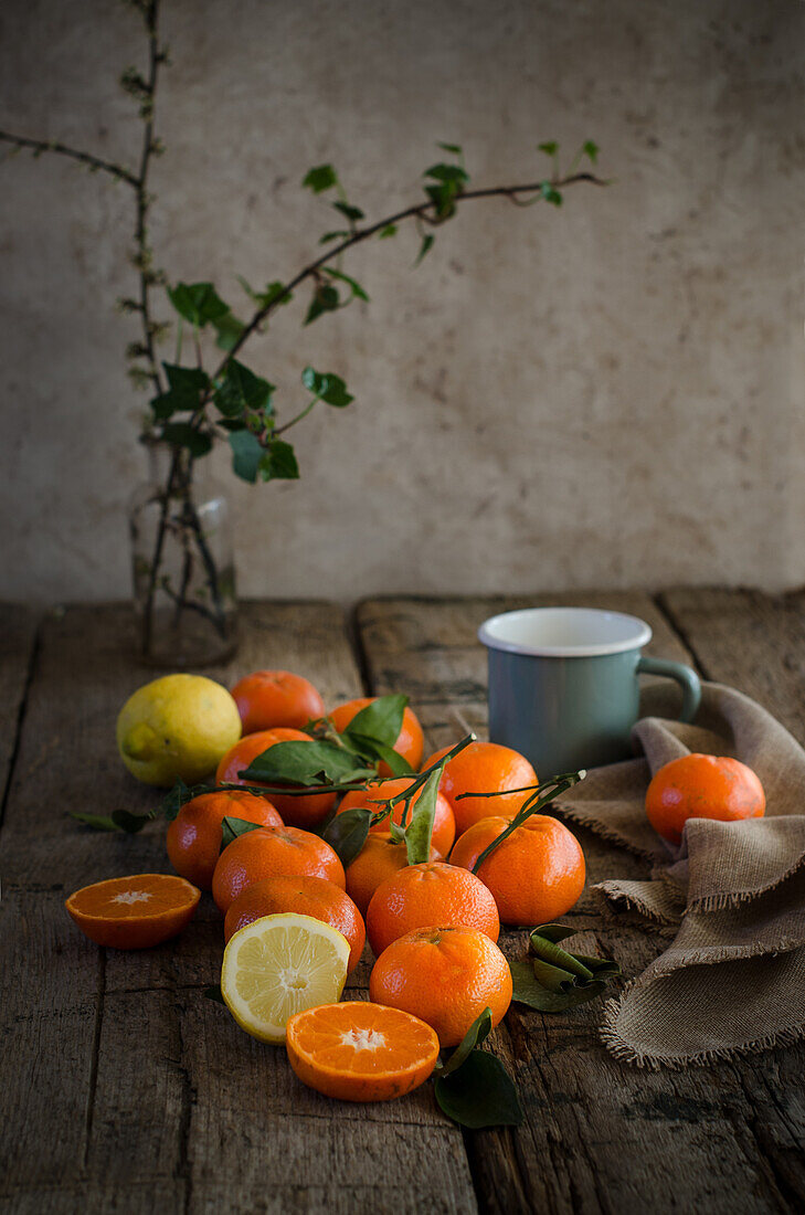Reife Mandarinen und Zitronen auf einem Holztisch mit Tasse und Serviette für die Zubereitung von Mousse