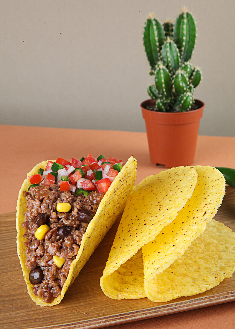 Hackfleisch-Tacos mit Mais und Soße auf einem Holztablett