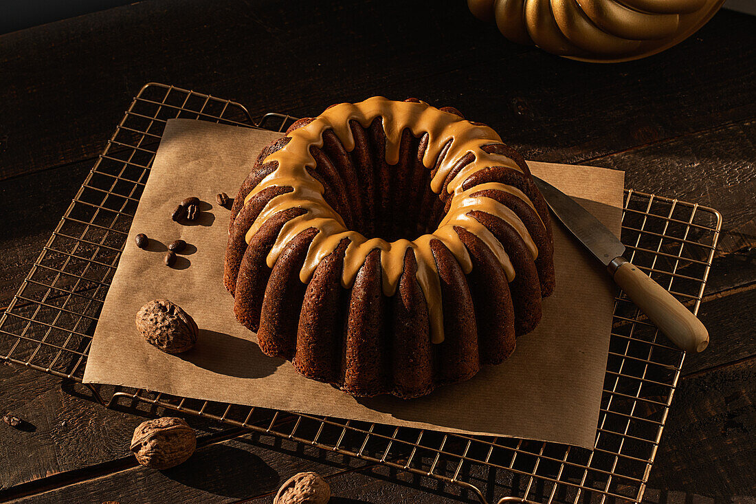 From above coffee walnut bundt cake placed on baking net on dark rustic wooden table in kitchen