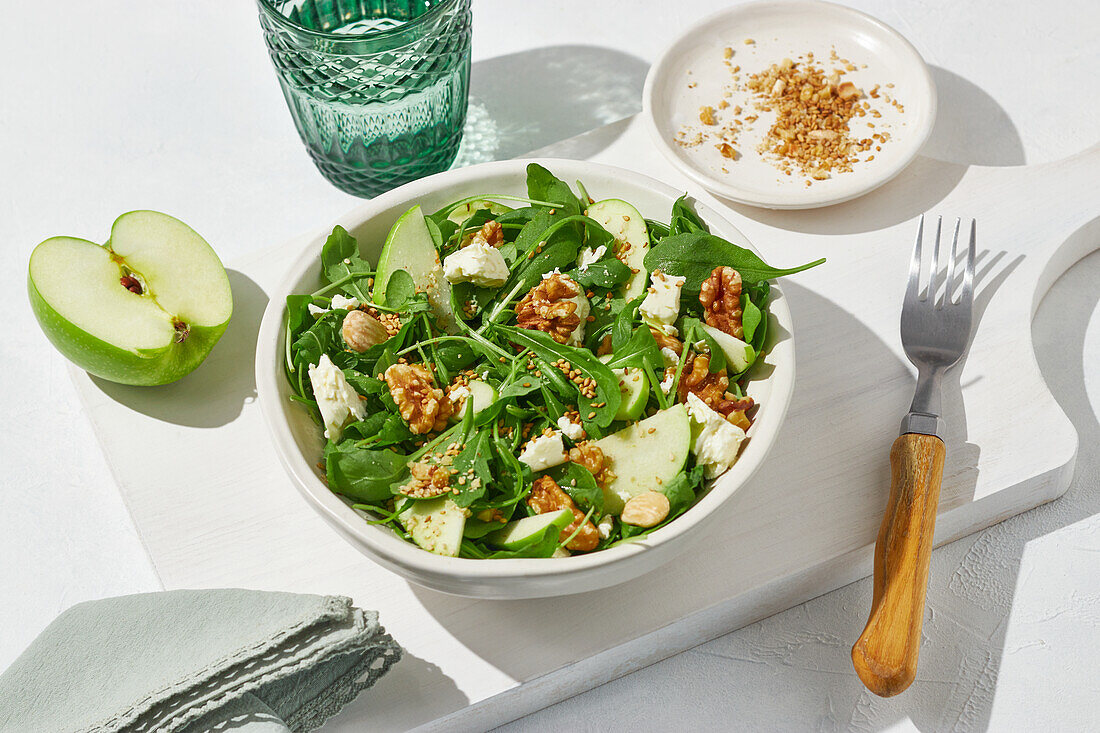 From above tasty green apple, feta cheese and walnut with lettuce salad served on white table background