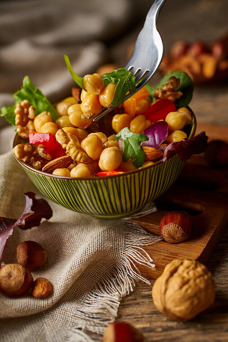 From above appetizing colorful cut vegetable mix with chickpeas and walnuts on wooden background