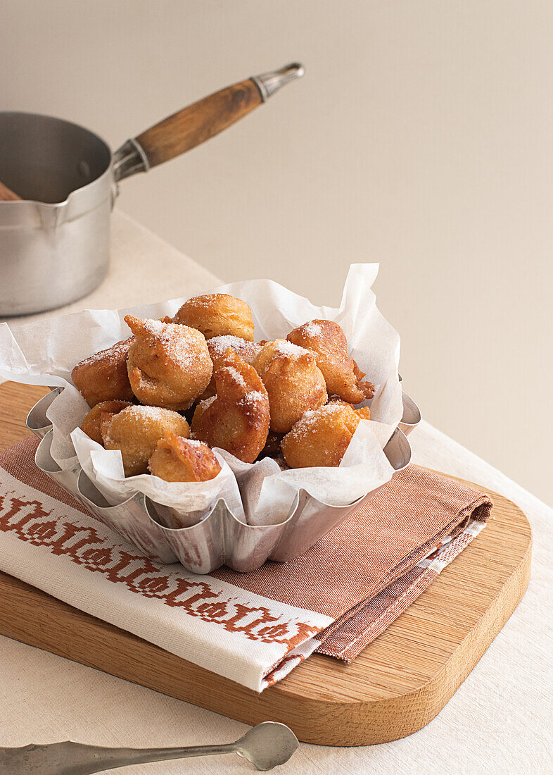 From above deep fried beignets doughnut placed on wooden tray on table in kitchen