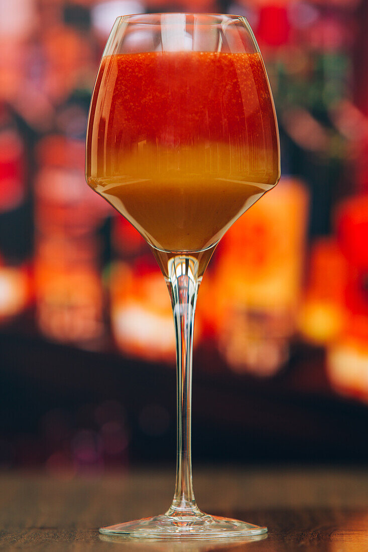 Nahaufnahme eines roten und orangefarbenen Cocktails vor unscharfem Hintergrund