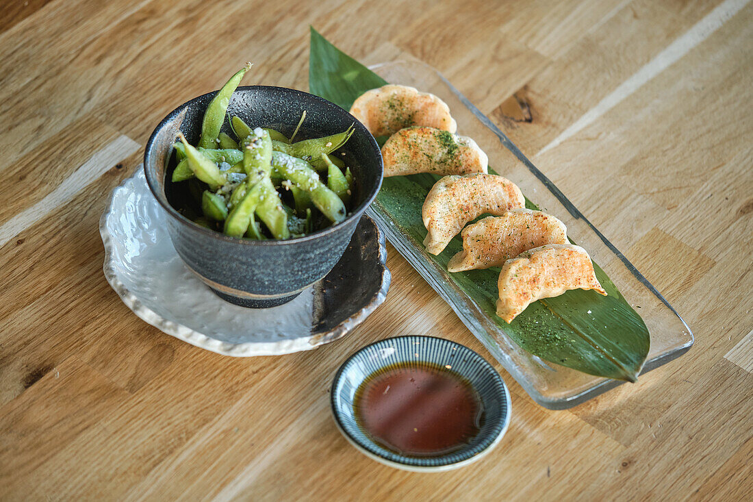 Stock photo of delicious plate of sushi and salted edamames in japanese restaurant.