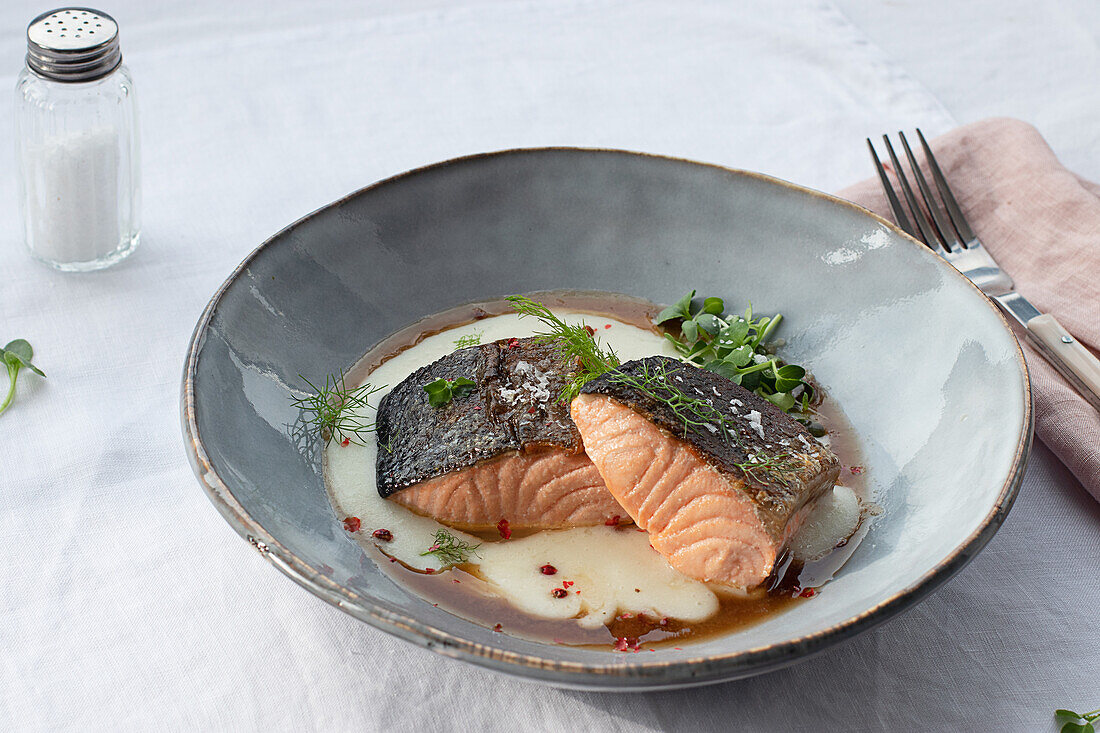 Von oben köstlicher Lachs mit Kartoffelpüree mit grünen Blättern und Gewürzen auf Keramikteller auf Tisch