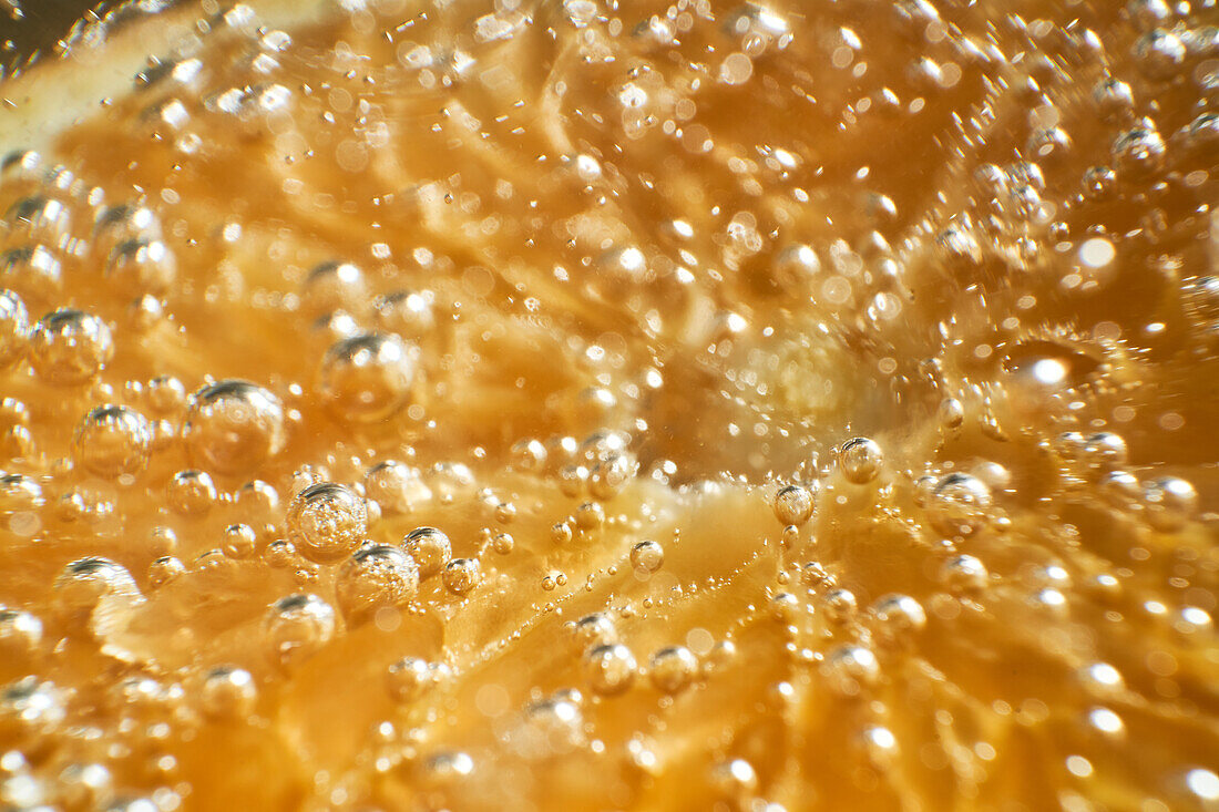 Close-up gin and tonic cocktail with slice of fresh orange bubbling in glass