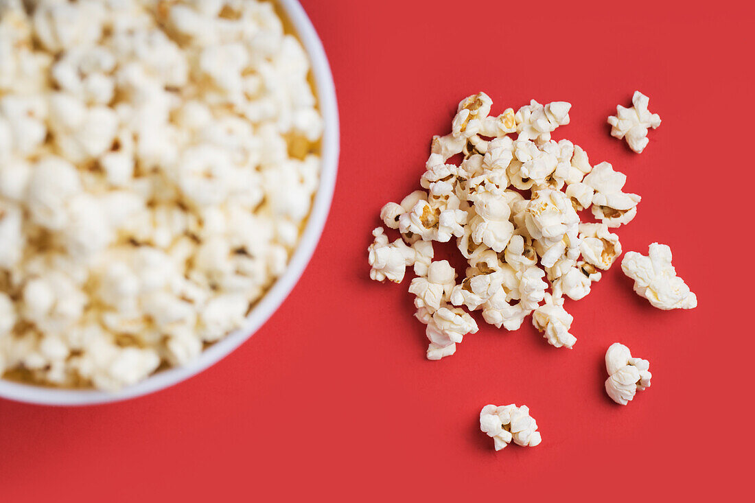 Draufsicht auf eine Schale mit Popcorn auf rotem Hintergrund