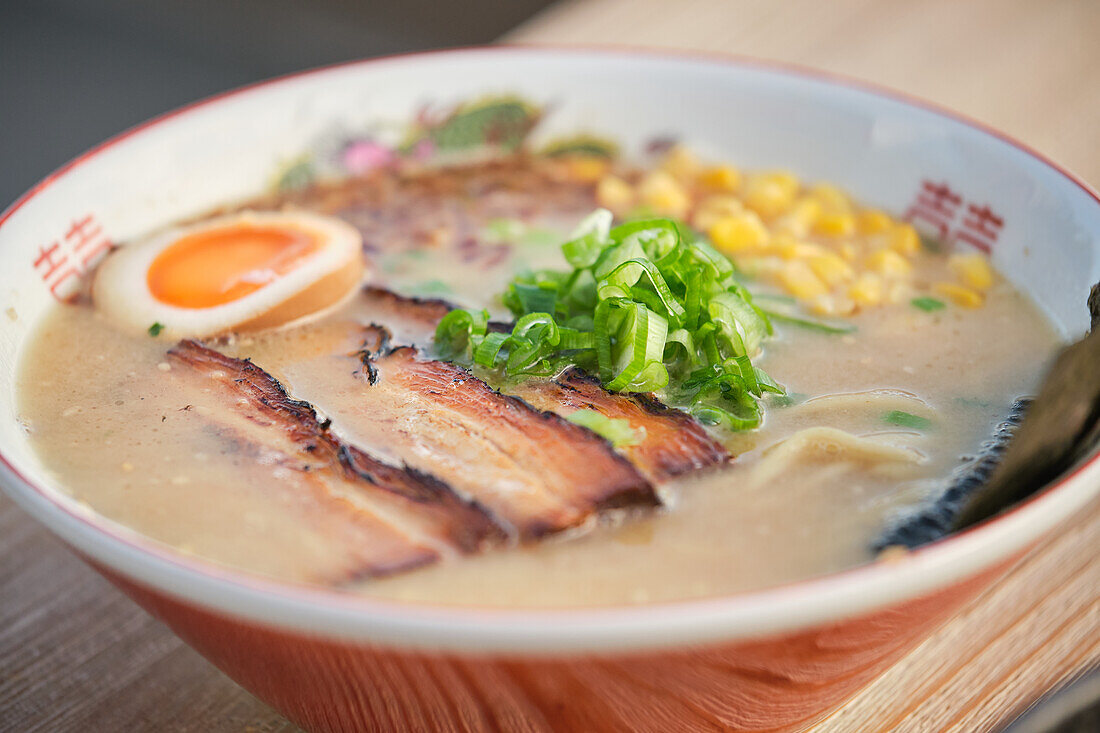 Stock photo of yummy ramen soup with boiled egg and meat in japanese restaurant ready to be served.