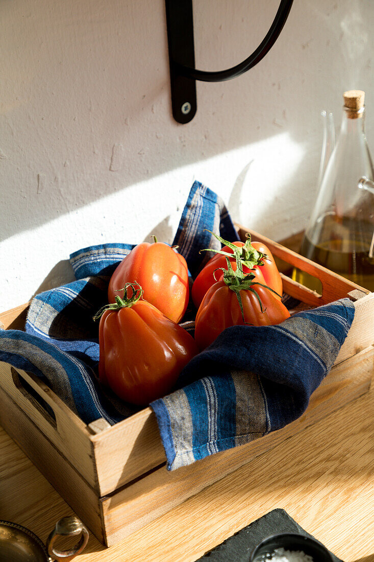 High angle of fresh ripe red tomatoes placed on natural wooden tray with napkin in home kitchen