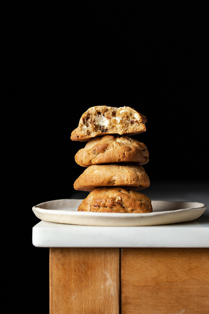 Stack of brown freshly baked cookies served on plate on corner of table in kitchen against black background in kitchen