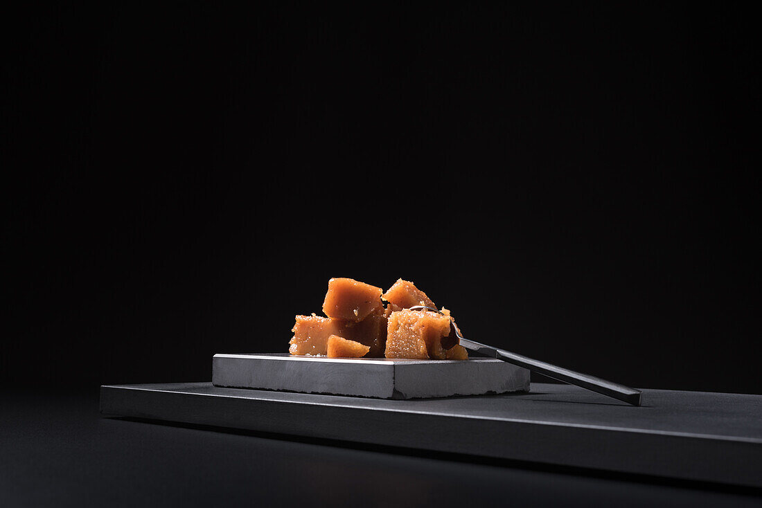 Gourmet quince jelly paste in ceramic plate on black background with spoon