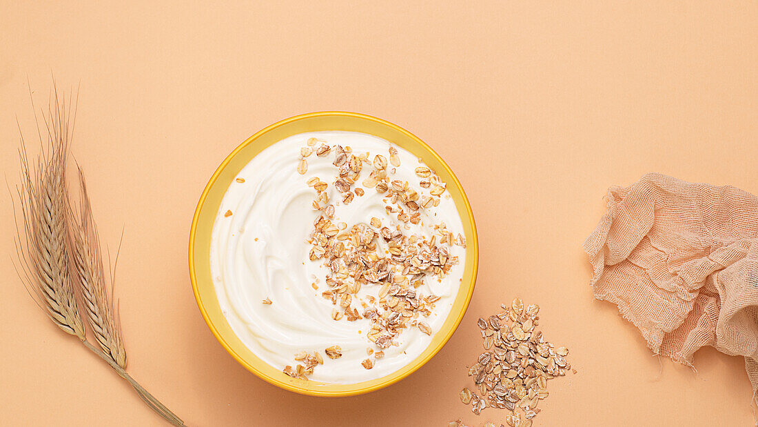 From above yoghurt served with dried oats on brown background