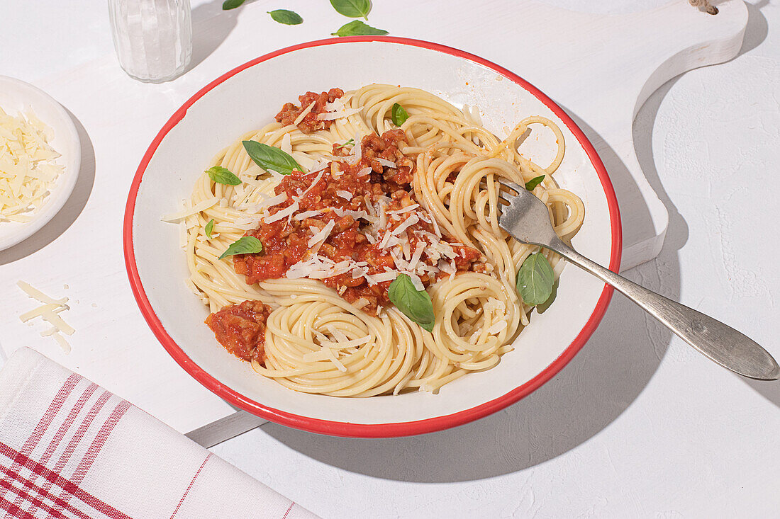 Top view of plate with spaghetti Bolognese pasta with tomatoes sauce in white table background