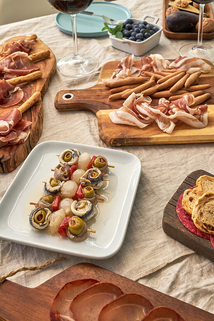 From above of assorted tasty appetizers served on table with tablecloth on terrace