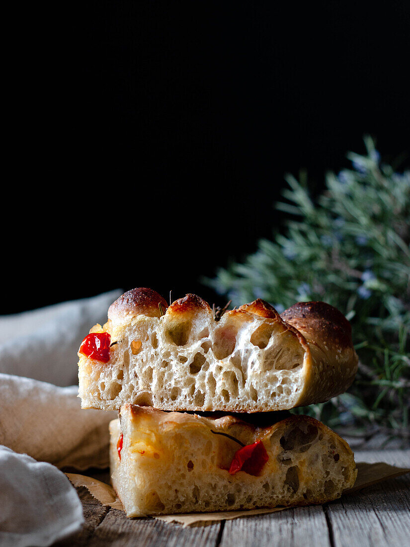 Nahaufnahme von einem Stück frischer Tomaten-Focaccia mit Rosmarin