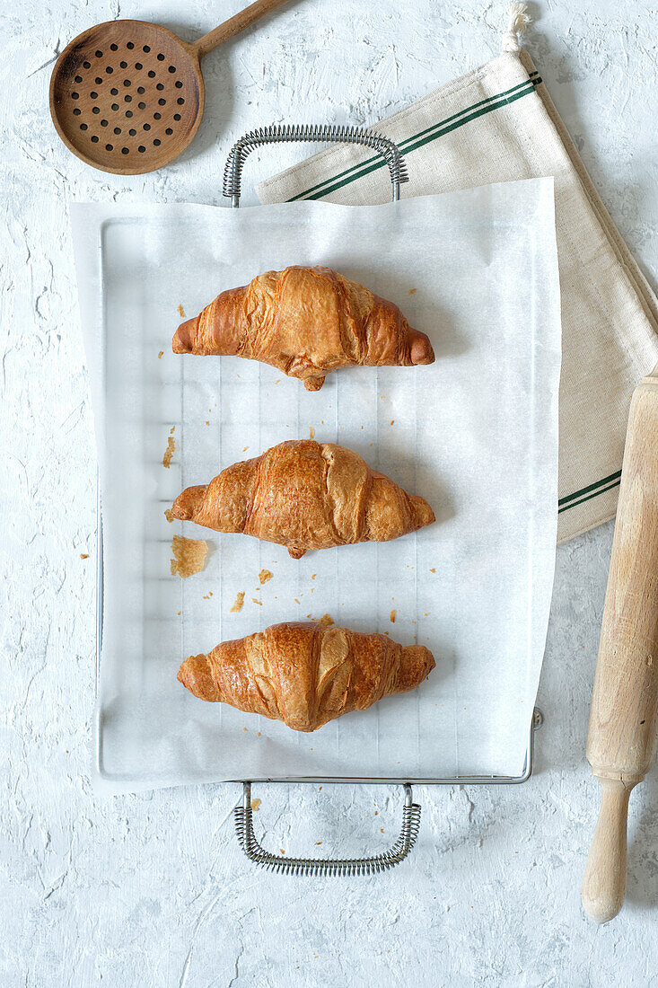 Top view of yummy fresh croissants placed on metal tray on table in kitchen