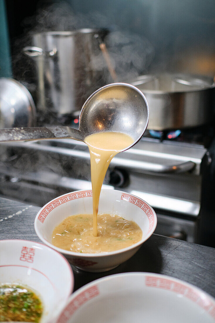 Stockfoto eines unbekannten Kochs in einem japanischen Restaurant, der Nudelsuppe serviert