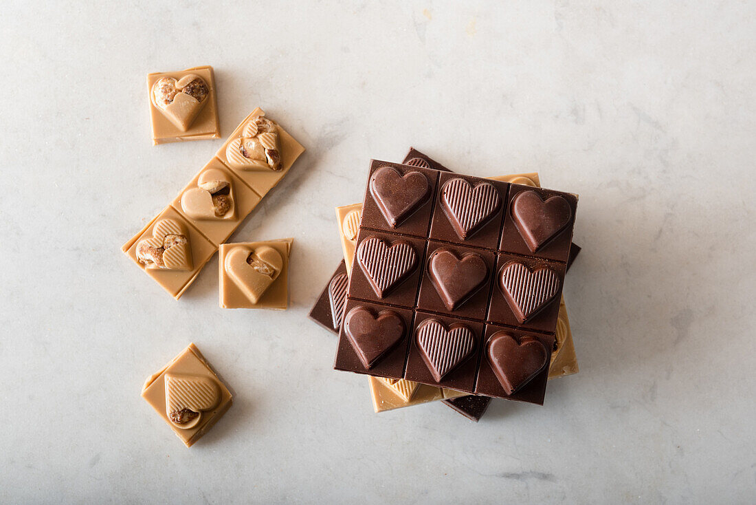 Top view of delicious chocolate candies with nuts in shape of heart scattered on white background