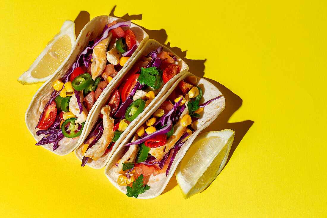 Hausgemachte mexikanische Tacos mit frischem Gemüse und Huhn mit starkem Licht auf gelbem Hintergrund. Gesundes Essen. Typisch mexikanisch