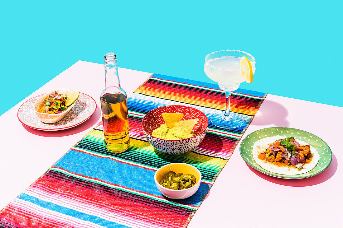 From above bottle of beer and glass of lemonade placed near assorted dishes on Mexican cuisine on table
