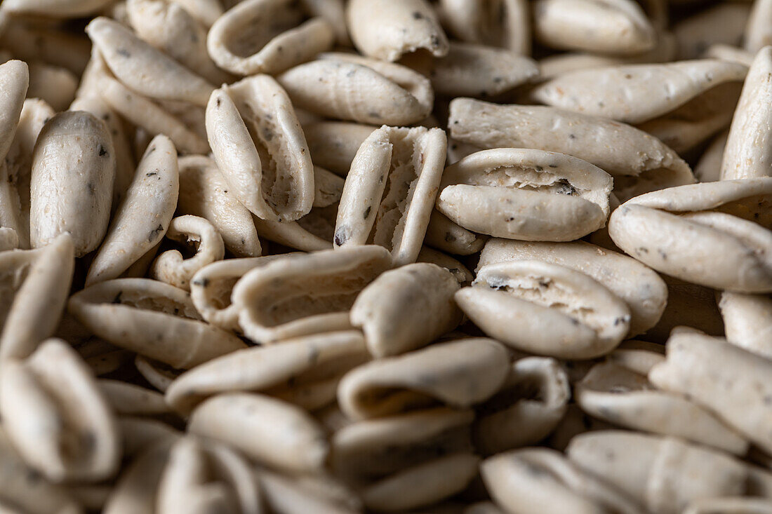 Full frame high angle of raw Basil cavatelli pasta scattered on smooth surface