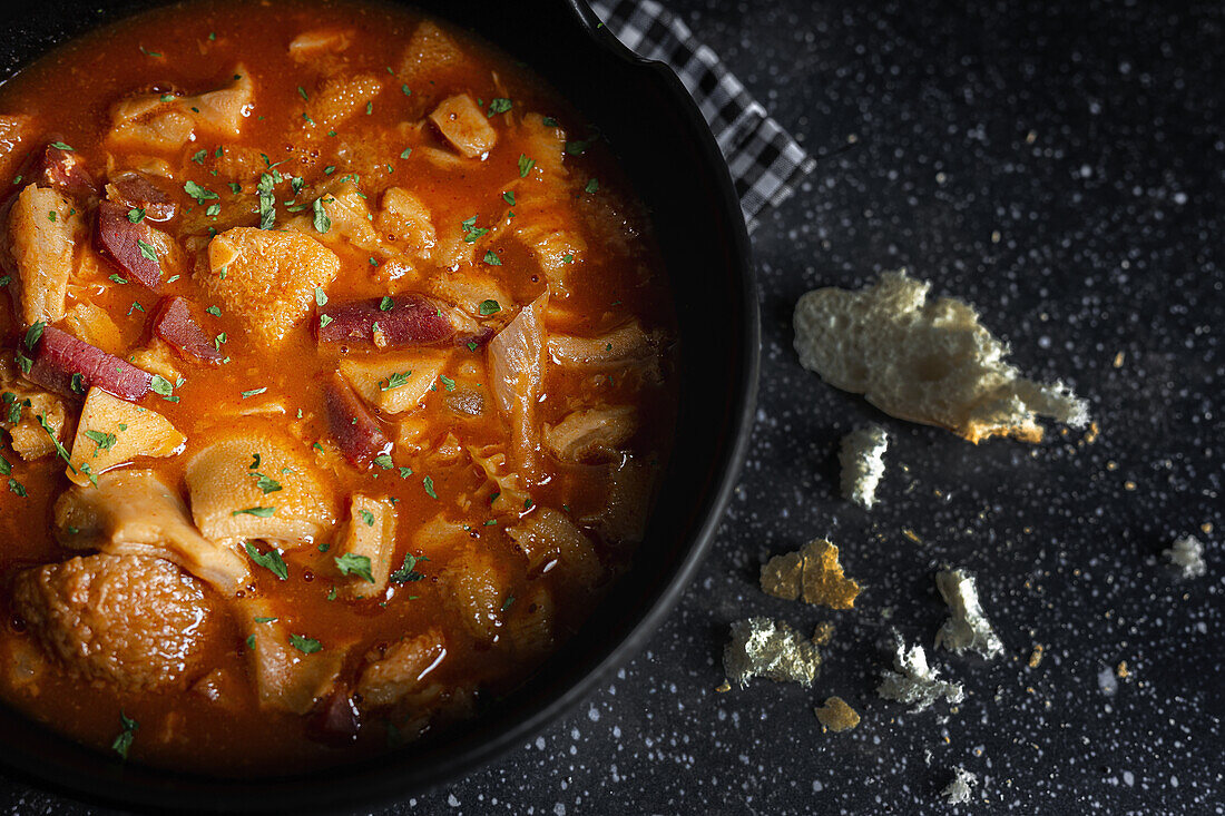 Leckere Callos a la Madrilena in einer schwarzen Schale auf einem Tisch mit Serviette von oben