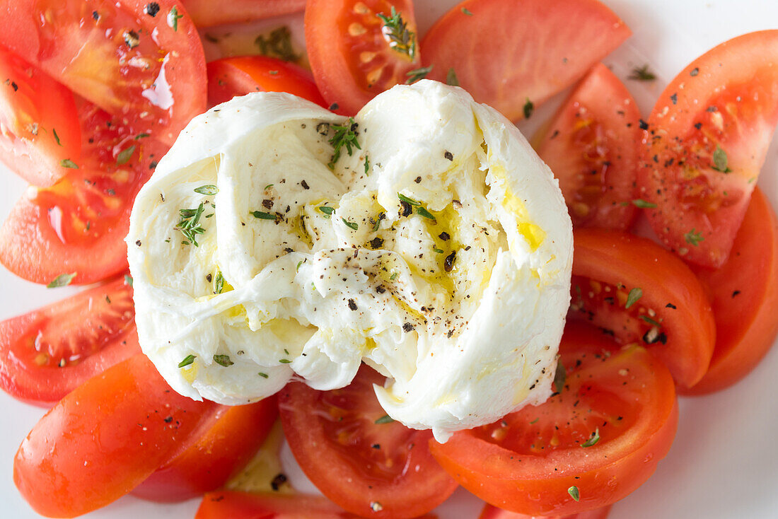 Von oben Nahaufnahme von reifen Tomatenscheiben und Mozzarella-Käse, serviert auf weißem Teller