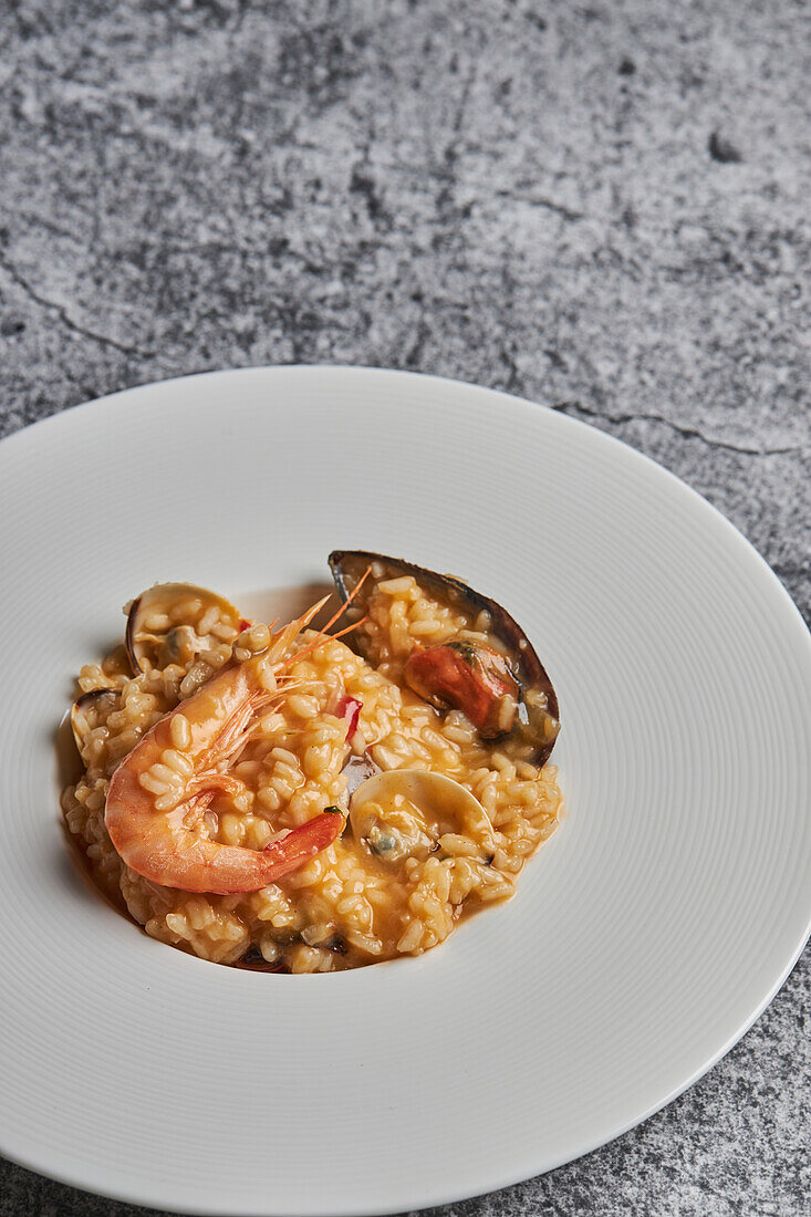 From above of appetizing rice with assorted seafood served on plate on table in restaurant