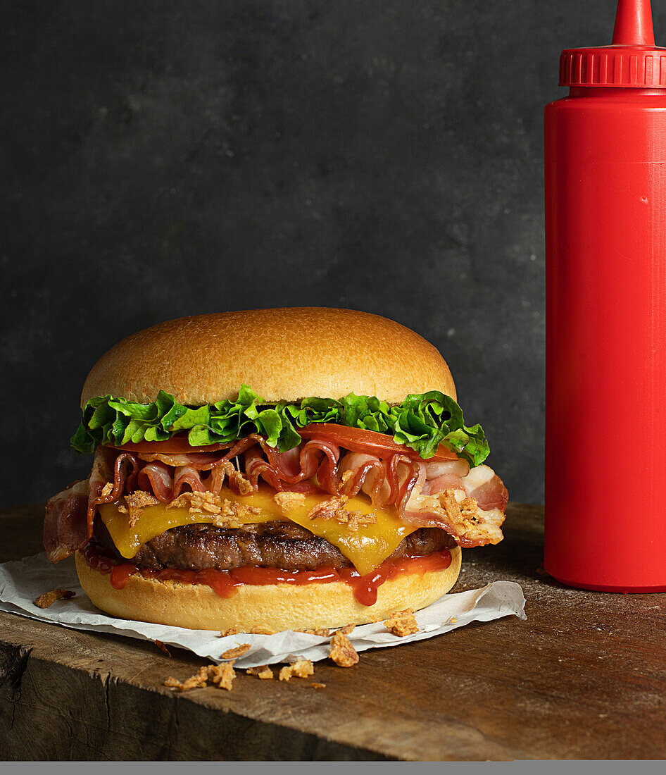 Detail of a delicious burger with cheese and bacon on the wooden table