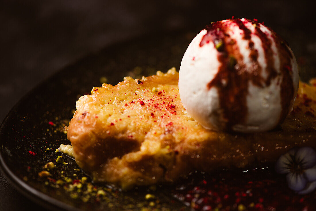 Nahaufnahme von leckerem French Toast mit Baiser-Milch-Eiskugel, bedeckt mit süßer Beerensoße auf Teller mit Gewürzen in Restaurant auf dunklem Hintergrund