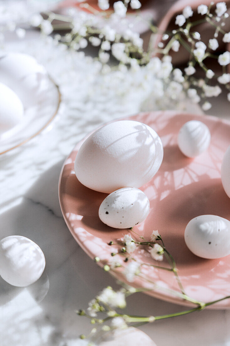 Von oben Stillleben von schön bemalten Ostereiern auf weißem Tischhintergrund neben süßen Blumen
