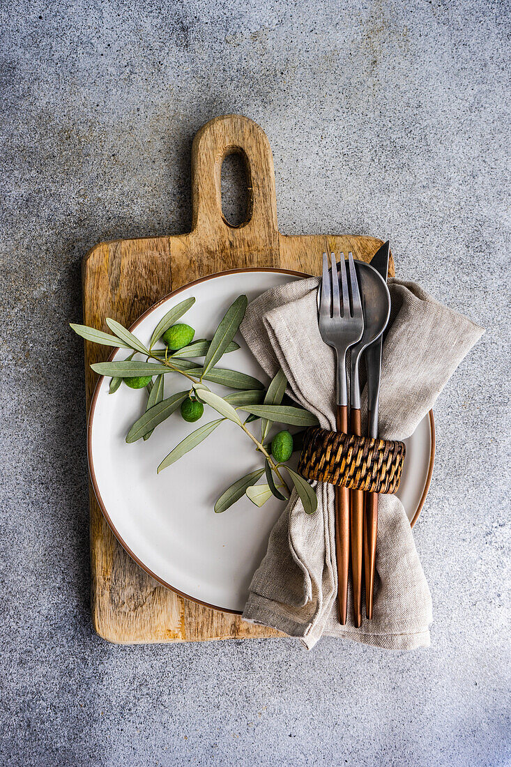 Rustic summer table setting with plate and cutlery decorated with Olive tree branches