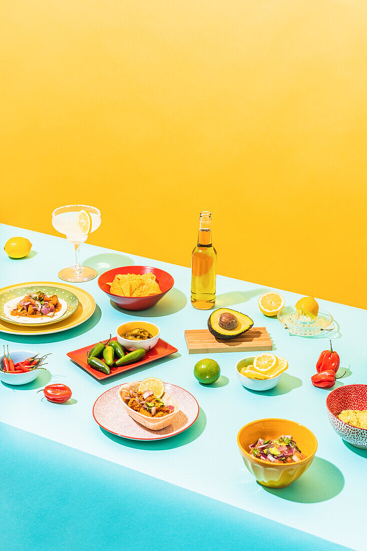 From above assorted traditional Mexican dishes and drinks placed on blue table near yellow wall