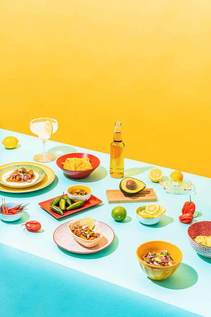 Verschiedene traditionelle mexikanische Gerichte und Getränke auf einem blauen Tisch an einer gelben Wand von oben