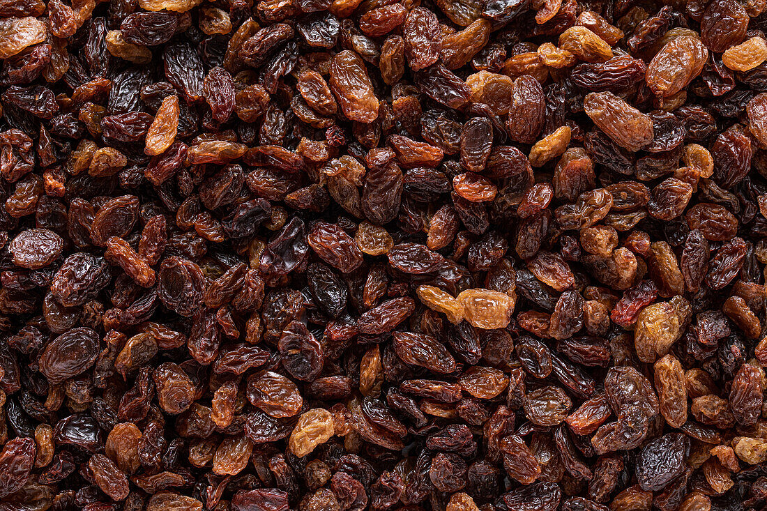 Full frame top view of heap of sweet multicolored dried sultana raisins placed on table