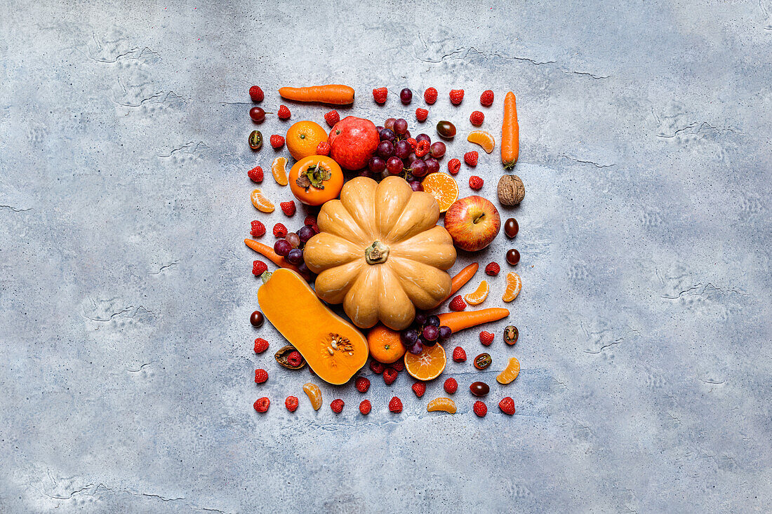 Stilleben mit verschiedenen Herbstgemüsesorten, Kürbissen, Äpfeln, Kaki, Mandarinen, Trauben und Haselnüssen von oben
